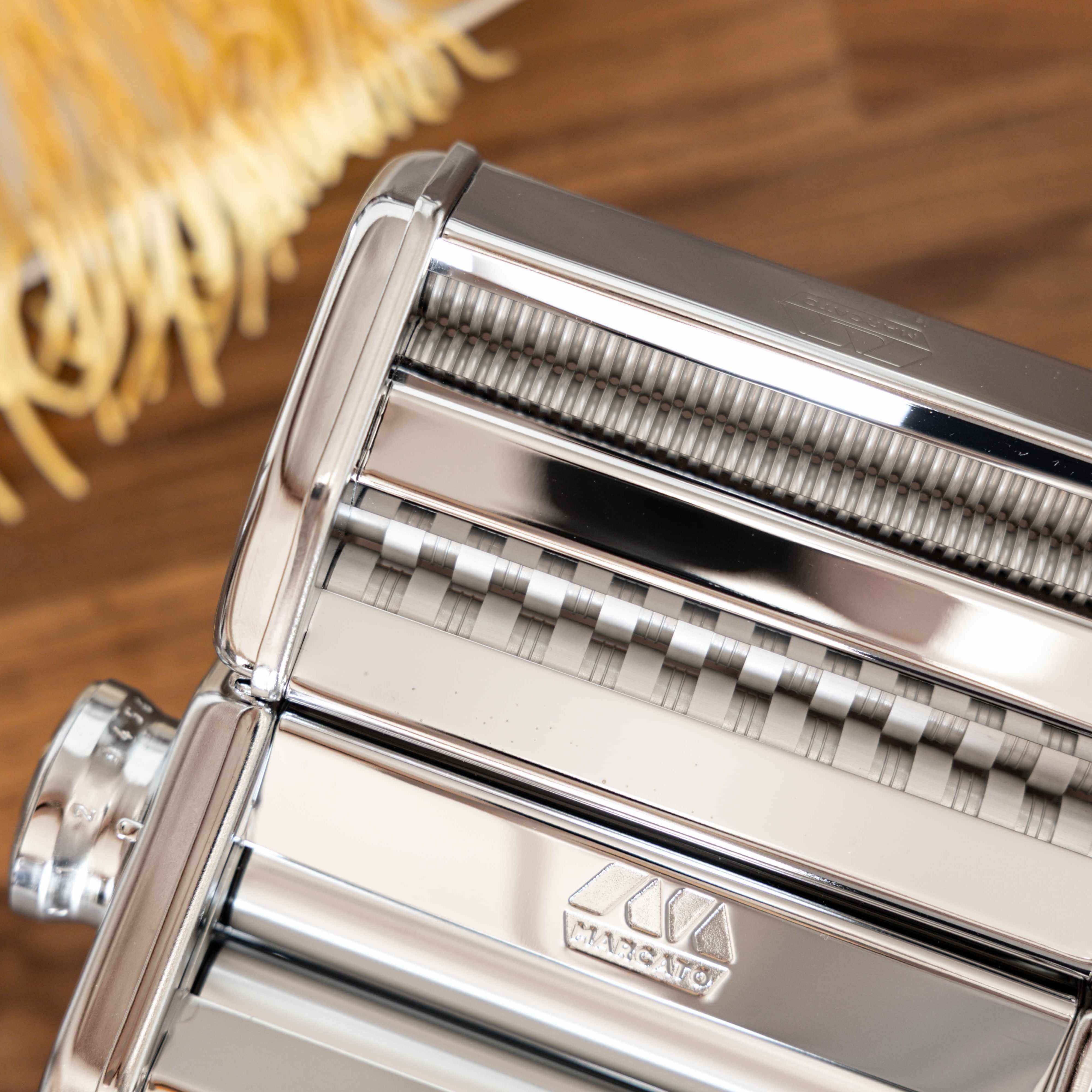 Pasta maker machine with pasta on a wooden surface