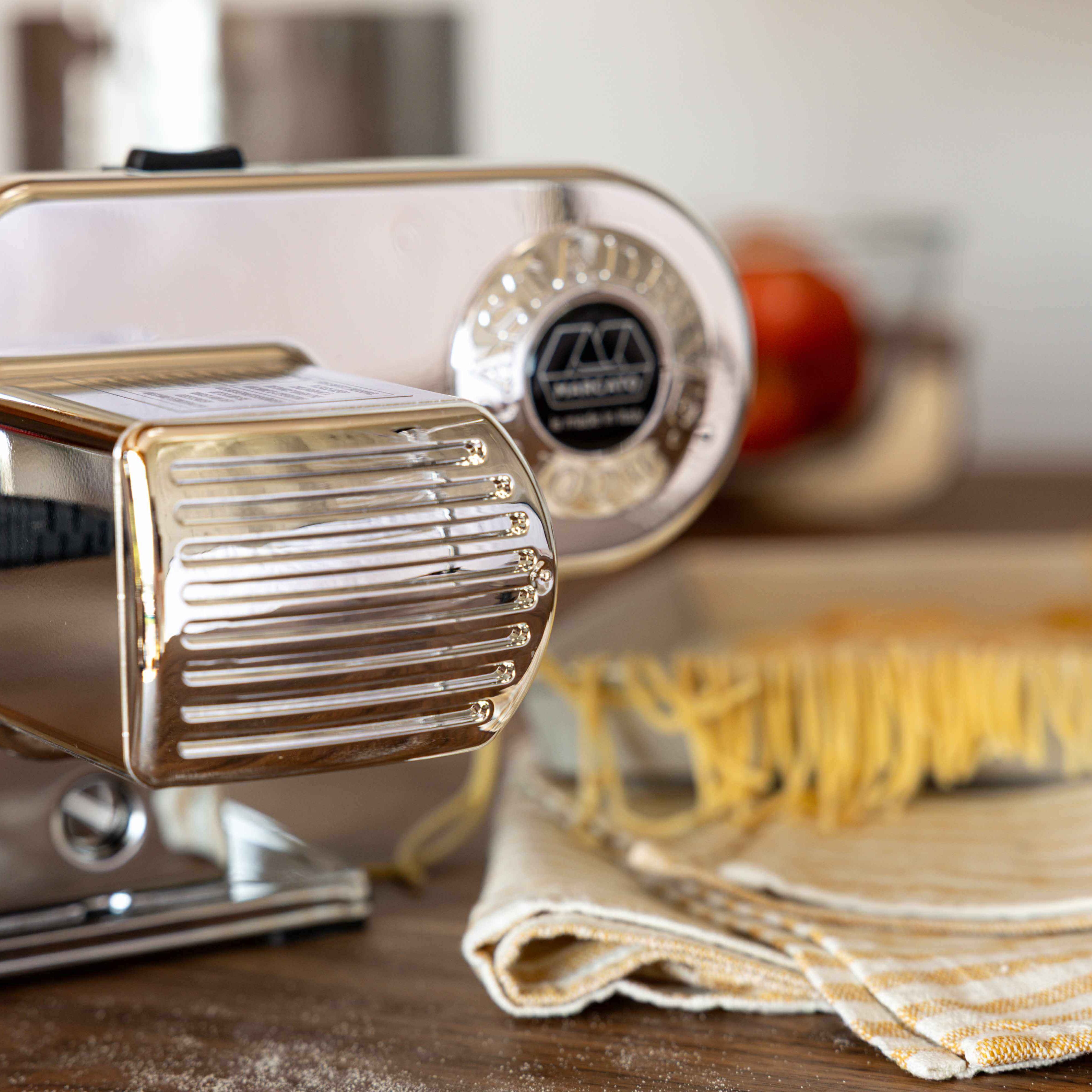 Pasta maker with fresh pasta on a kitchen counter