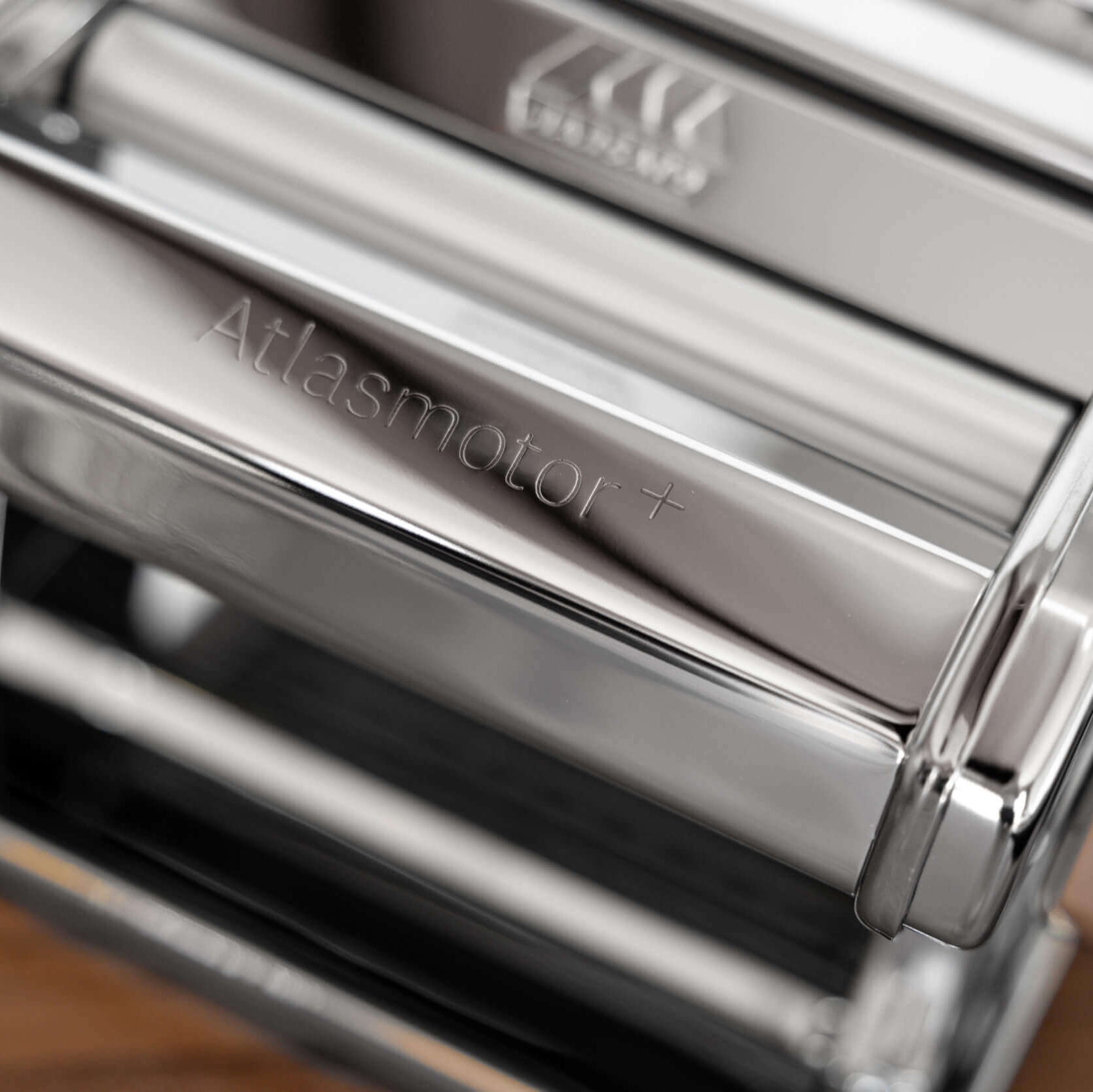 Close-up of a pasta maker with 'Atlas Motor+' branding on the rollers.