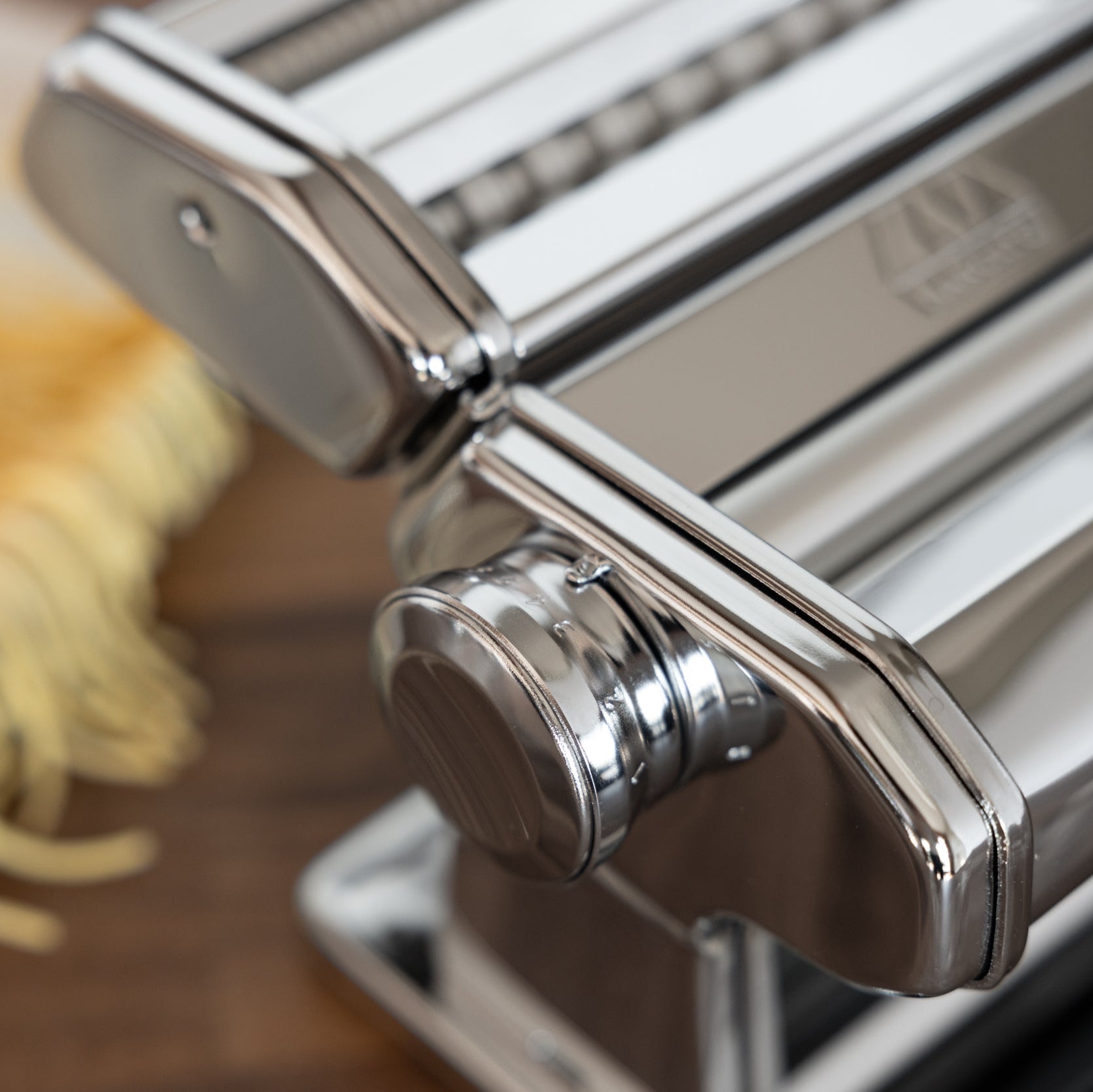 Marcato Atlas+ pasta maker with fresh pasta on a wooden surface