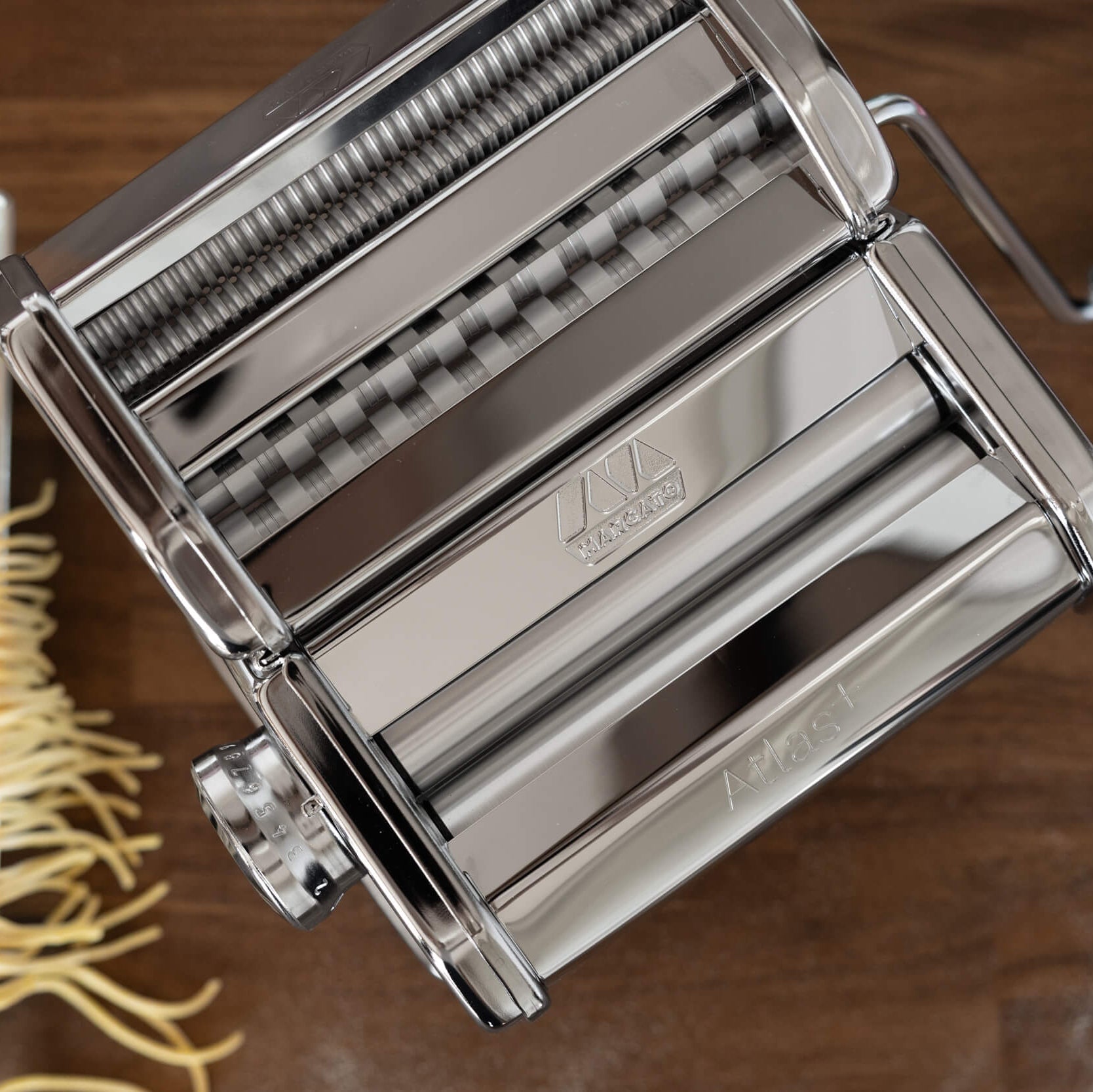 Pasta maker with fresh pasta on a wooden surface
