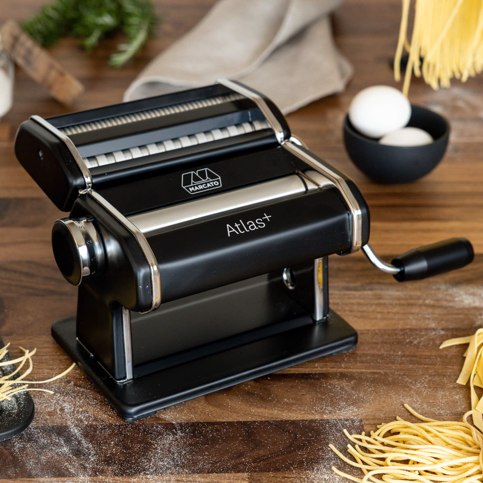 Pasta maker with fresh pasta on a wooden surface