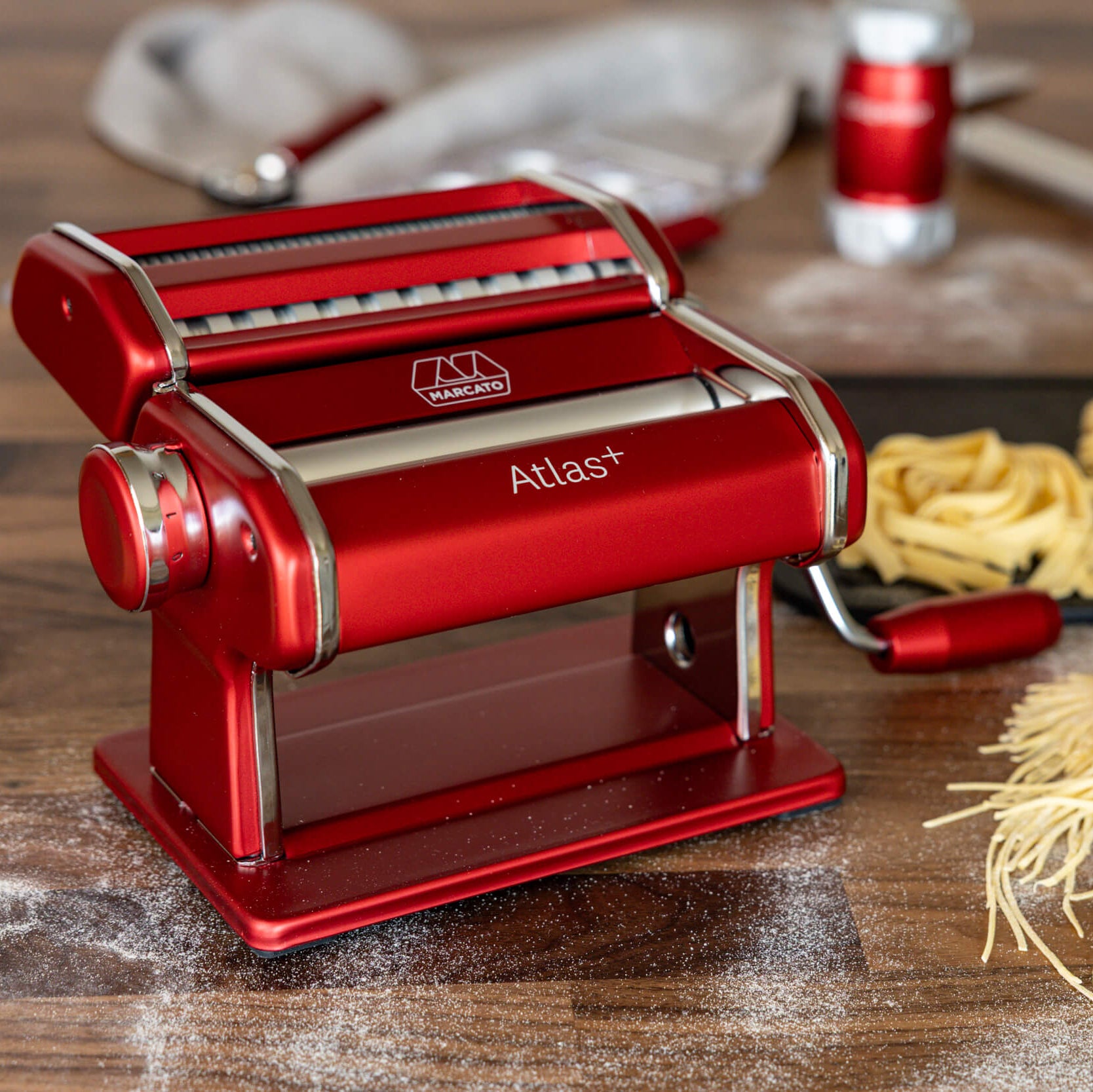 Red pasta maker with fresh pasta on a wooden surface