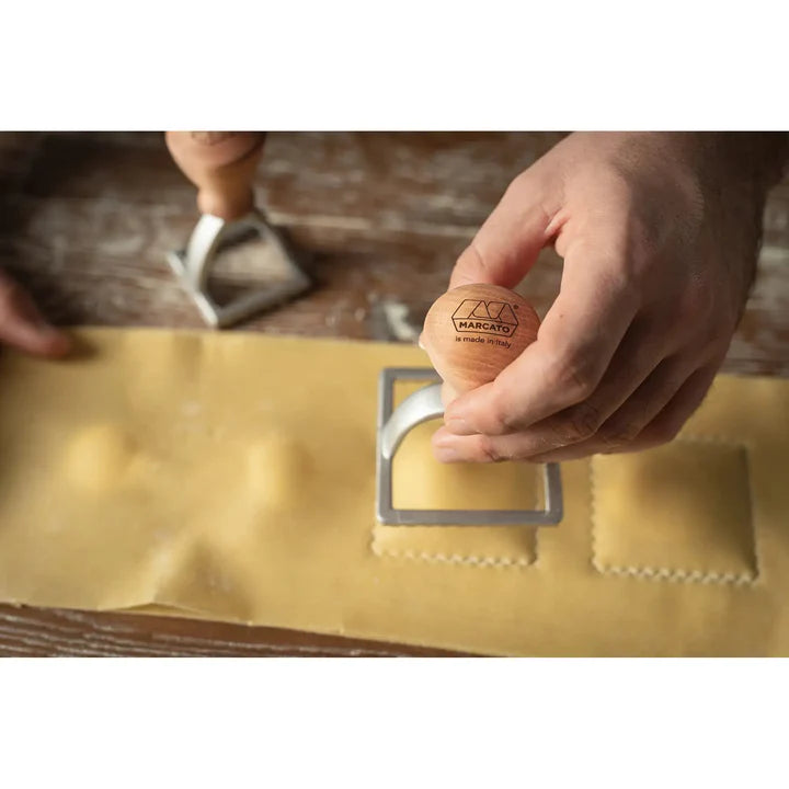 Hand using a stamp on pasta with a visible Marcato logo.