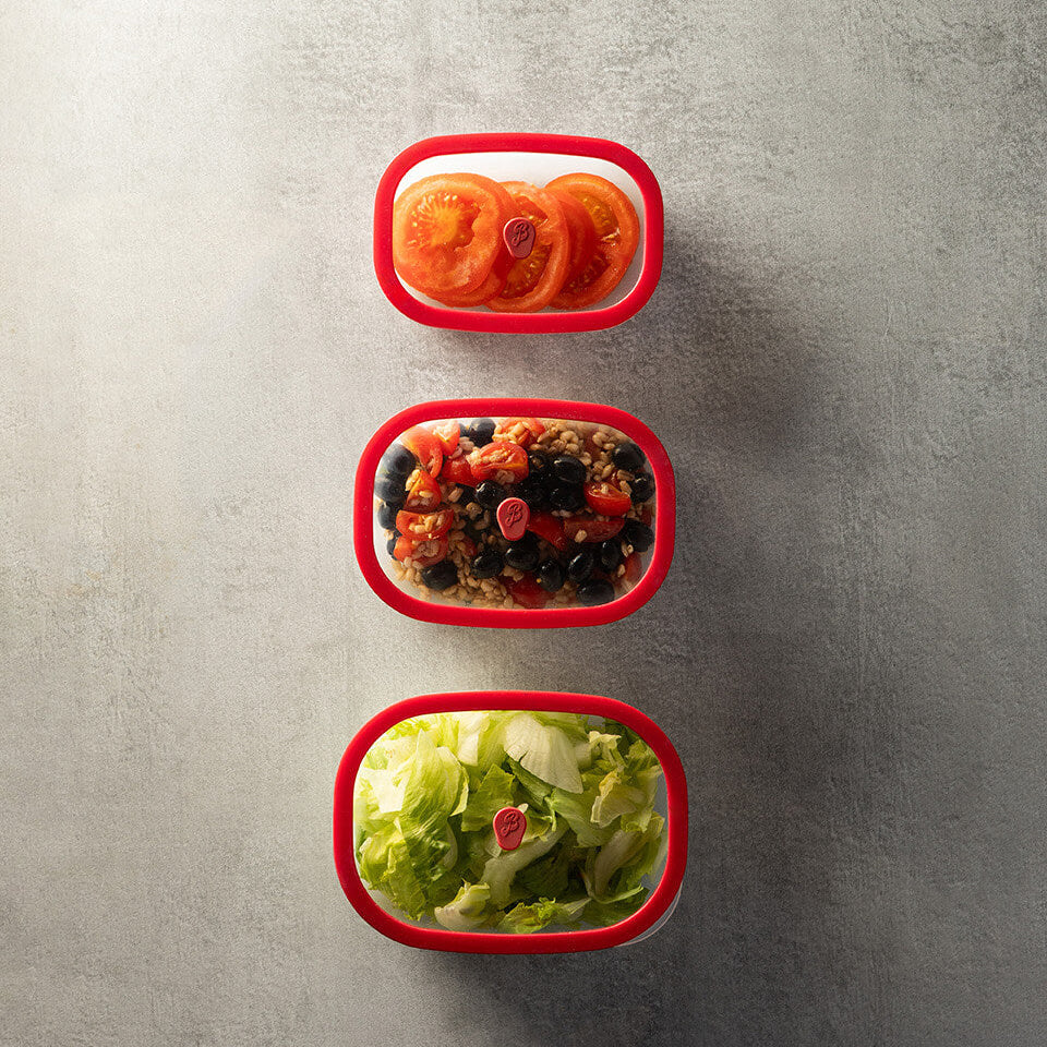 Three red Berkel vacuum containers with food on a gray surface